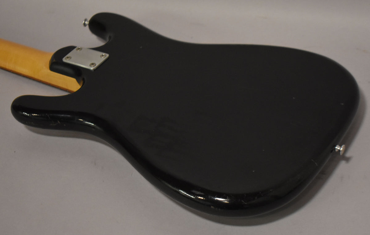 The black solidbody electric guitar's back shows finish checking, wear, and a chrome neck plate and strap button.
