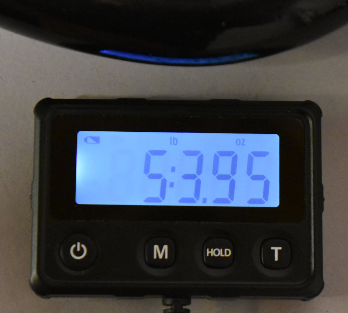 A digital scale displays "5:3.95 lb oz" with a dark guitar body partially visible above.