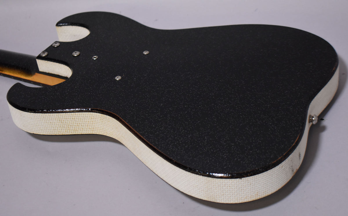 The guitar's textured black back and white textured sides are visible, with some wear and a chrome strap button on the lower bout.