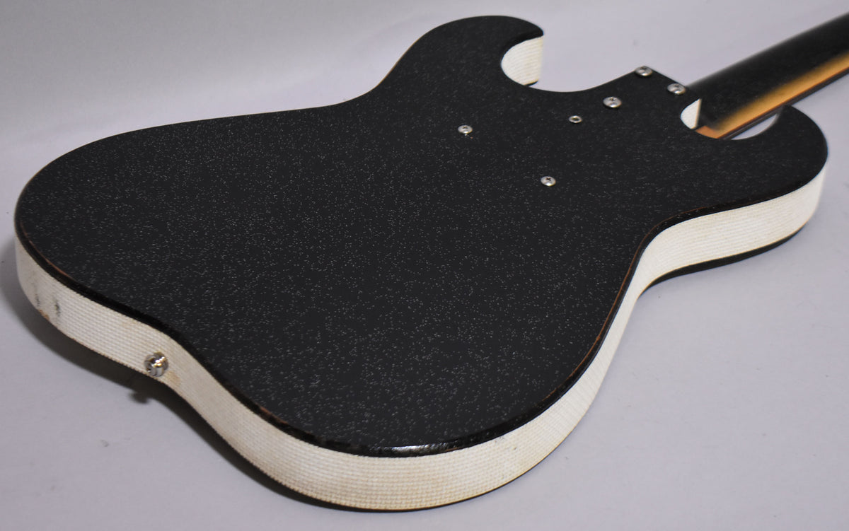The guitar's black sparkle back and white textured binding are visible, with four neck bolts and some wear on the lower bout.