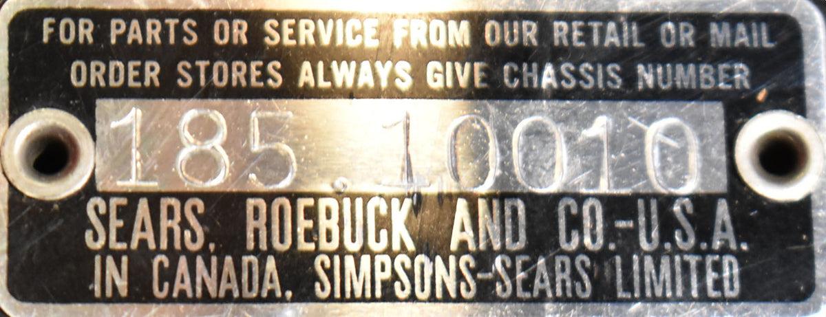 Close-up of the guitar's black and silver metal serial number plate, showing wear and two screw holes.