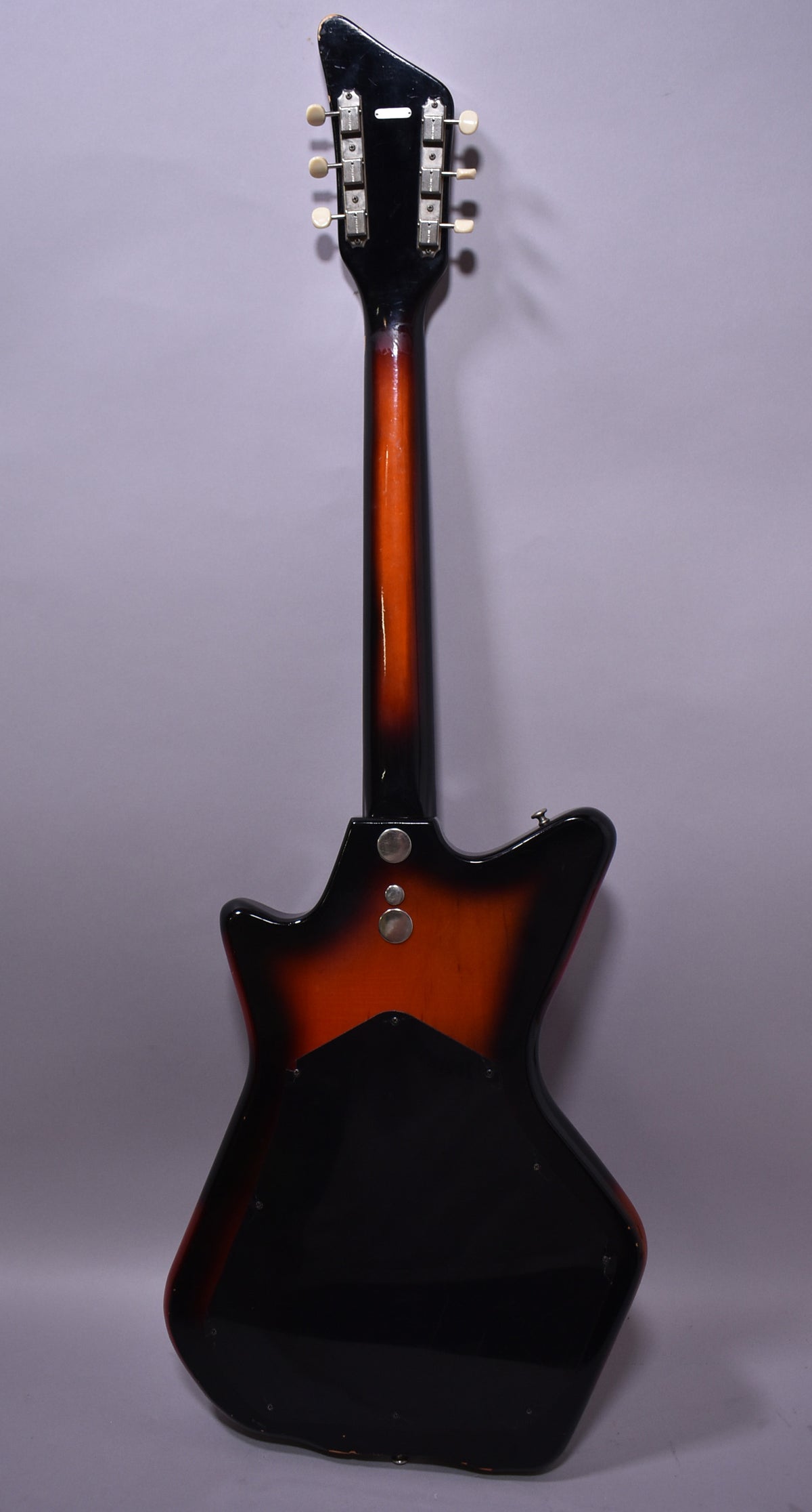 The guitar's back, a sunburst finish with a black body and orange center, shows a black headstock with six tuners.