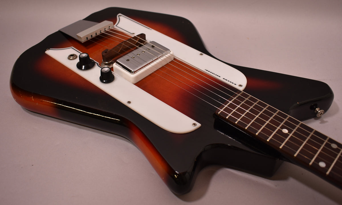A sunburst electric guitar with white pickguards, two black knobs, and a chrome pickup and bridge.