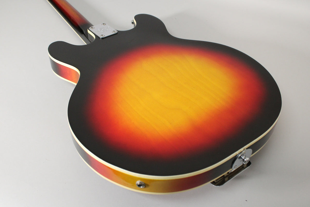 The guitar's sunburst back, with a bright yellow center fading to red and black, shows some light wear and a chrome output jack.
