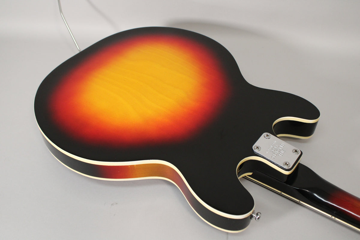 The guitar's sunburst back, with a chrome neck plate and strap button, shows minor scuffs and finish wear along the binding.