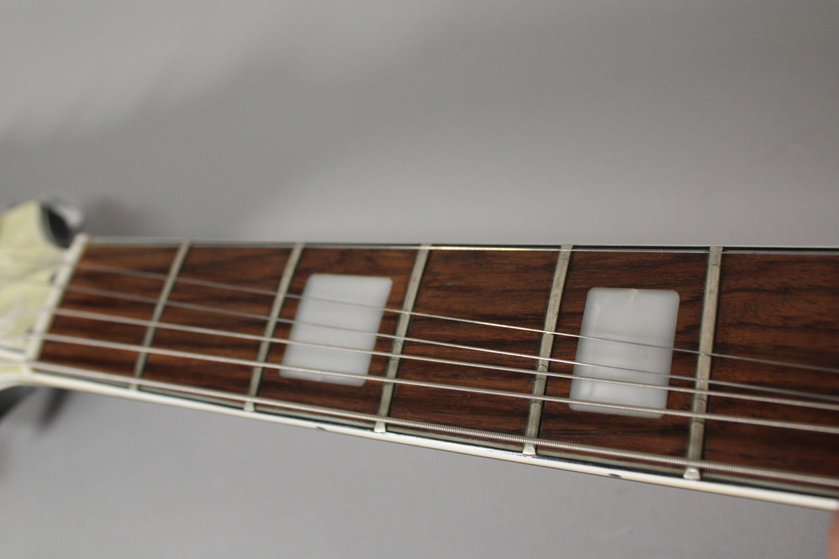 Close-up of the guitar's dark rosewood fretboard with rectangular white block inlays, showing some wear on the frets.