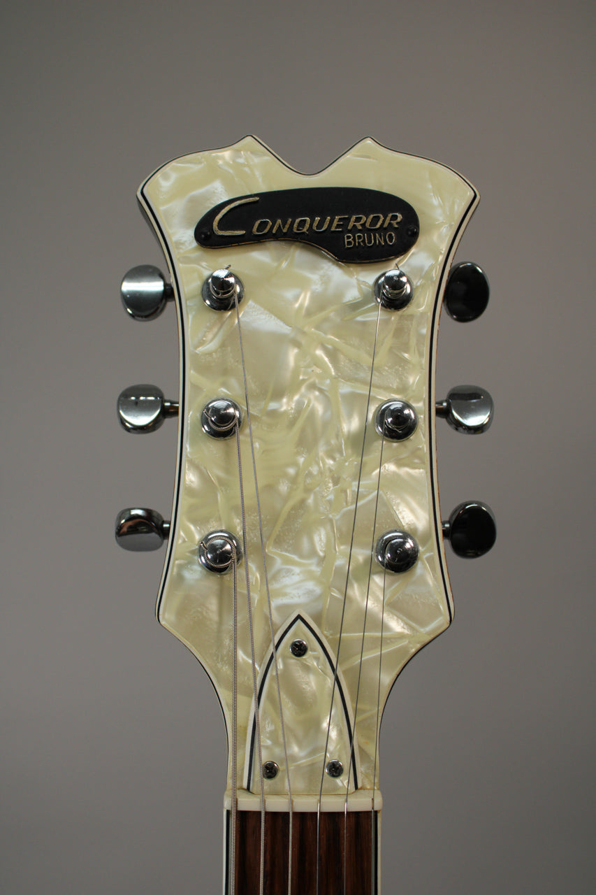 Close-up of the guitar's headstock, featuring a pearloid face, six chrome tuners, and a black truss rod cover.
