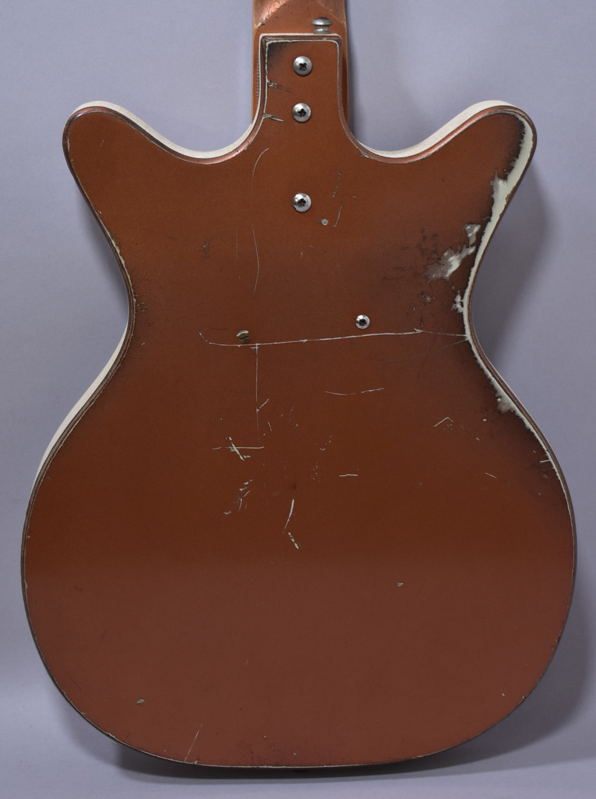 The back of the copper-finished bass shows heavy wear, with many scratches and large areas of paint chipped off the white binding.