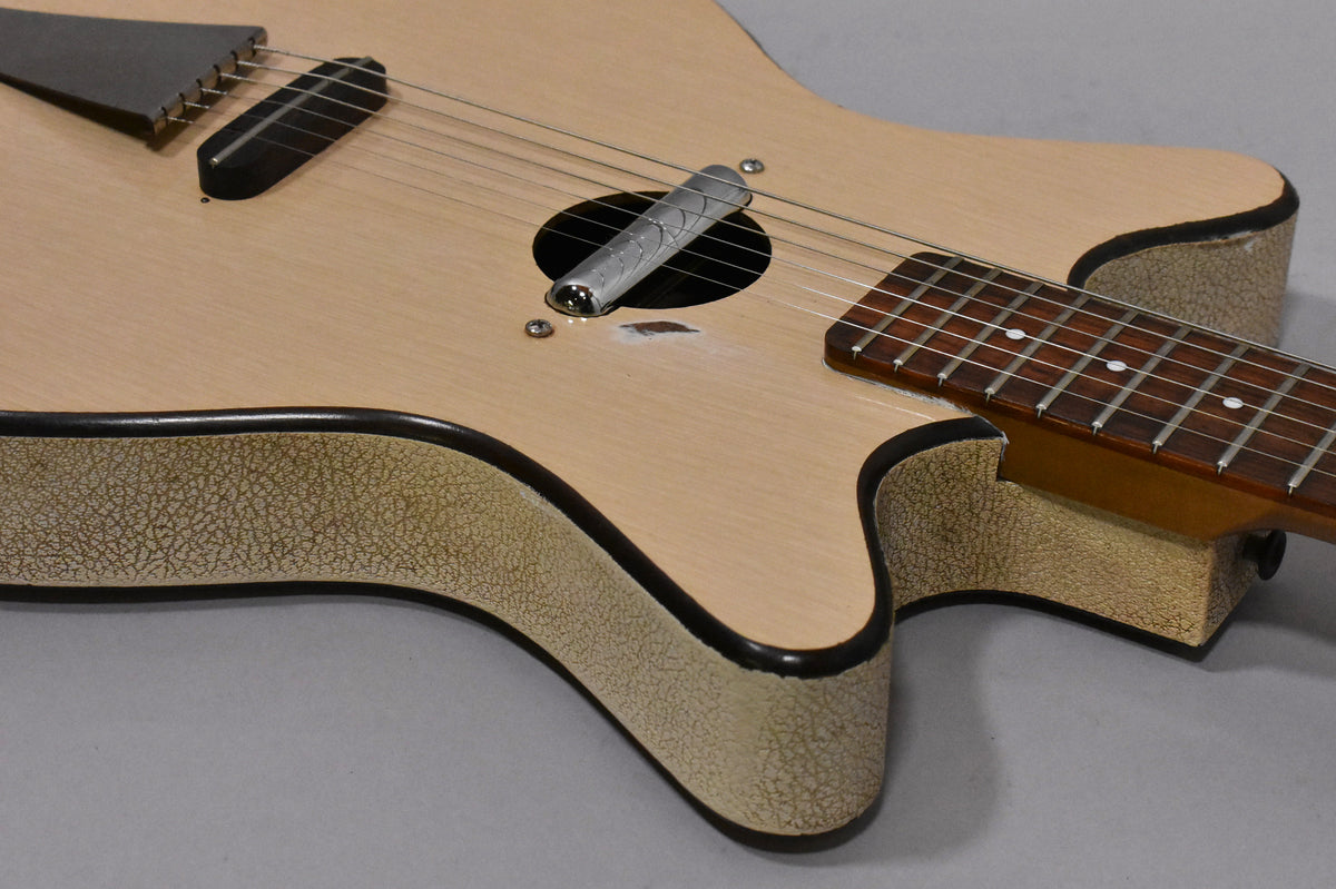 Close-up of the guitar's natural finish body and cracked cream binding, showing the soundhole, bridge, and neck pickup.