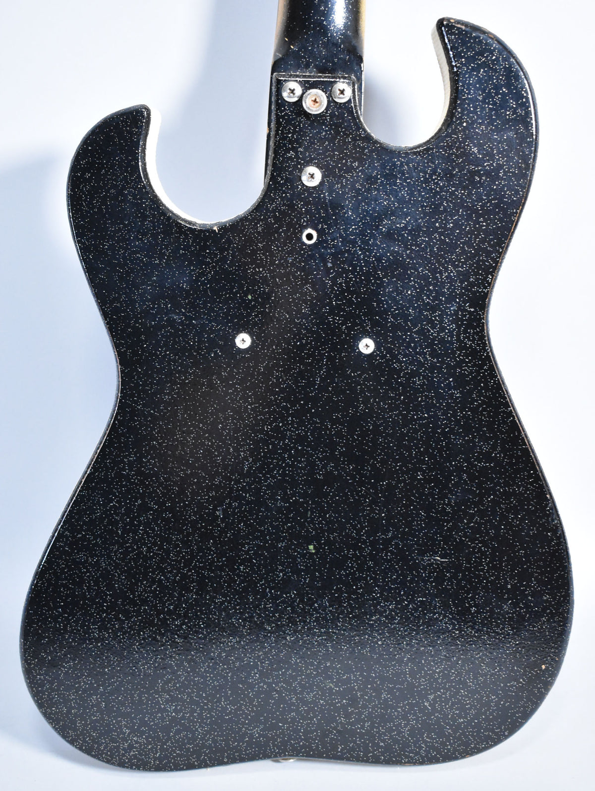 The back of a black sparkle-finish electric guitar, showing the neck joint and four visible screws on the body.