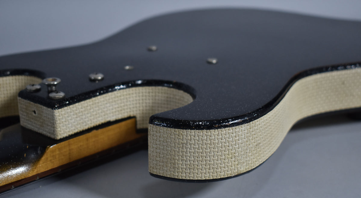 Close-up of the guitar's black sparkle body and cream textured sides, showing the neck joint and some minor wear on the binding.