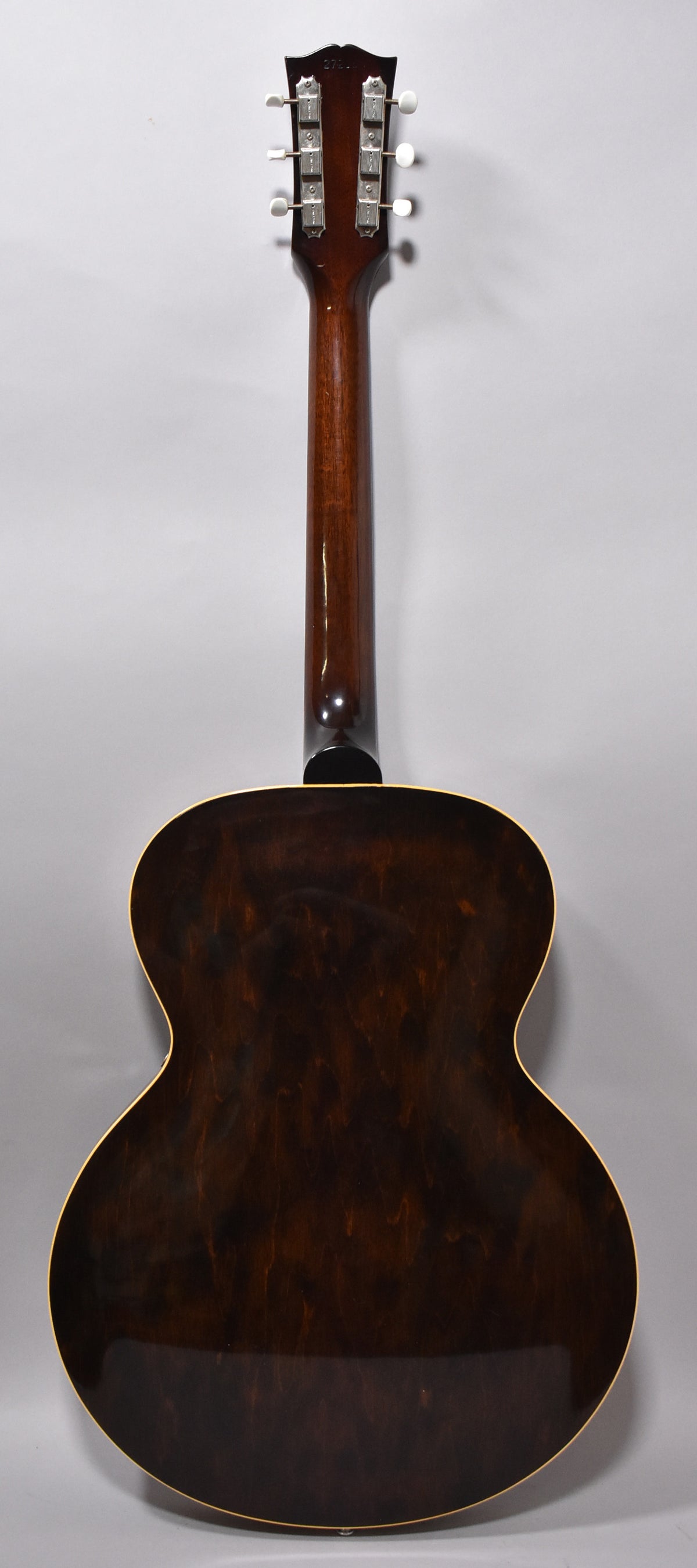 The back of a dark sunburst hollow-body guitar, showing the headstock, neck, and body with visible wood grain and light binding.