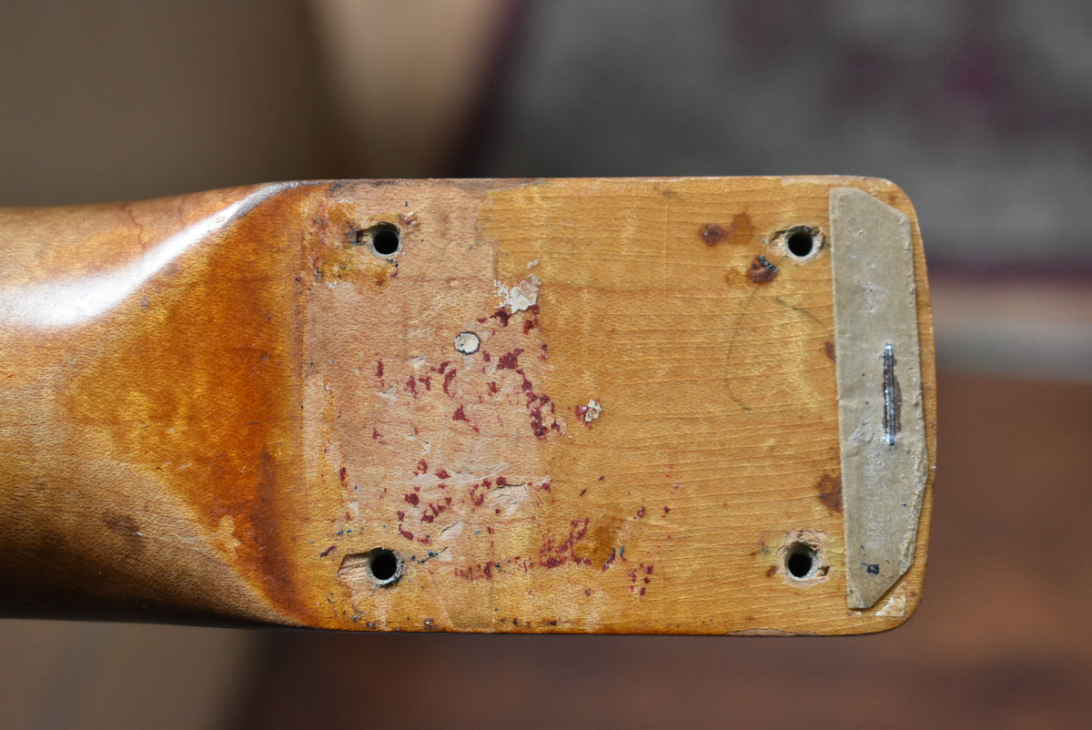 The guitar neck heel, showing four screw holes, worn wood, and remnants of red finish and a paper shim.