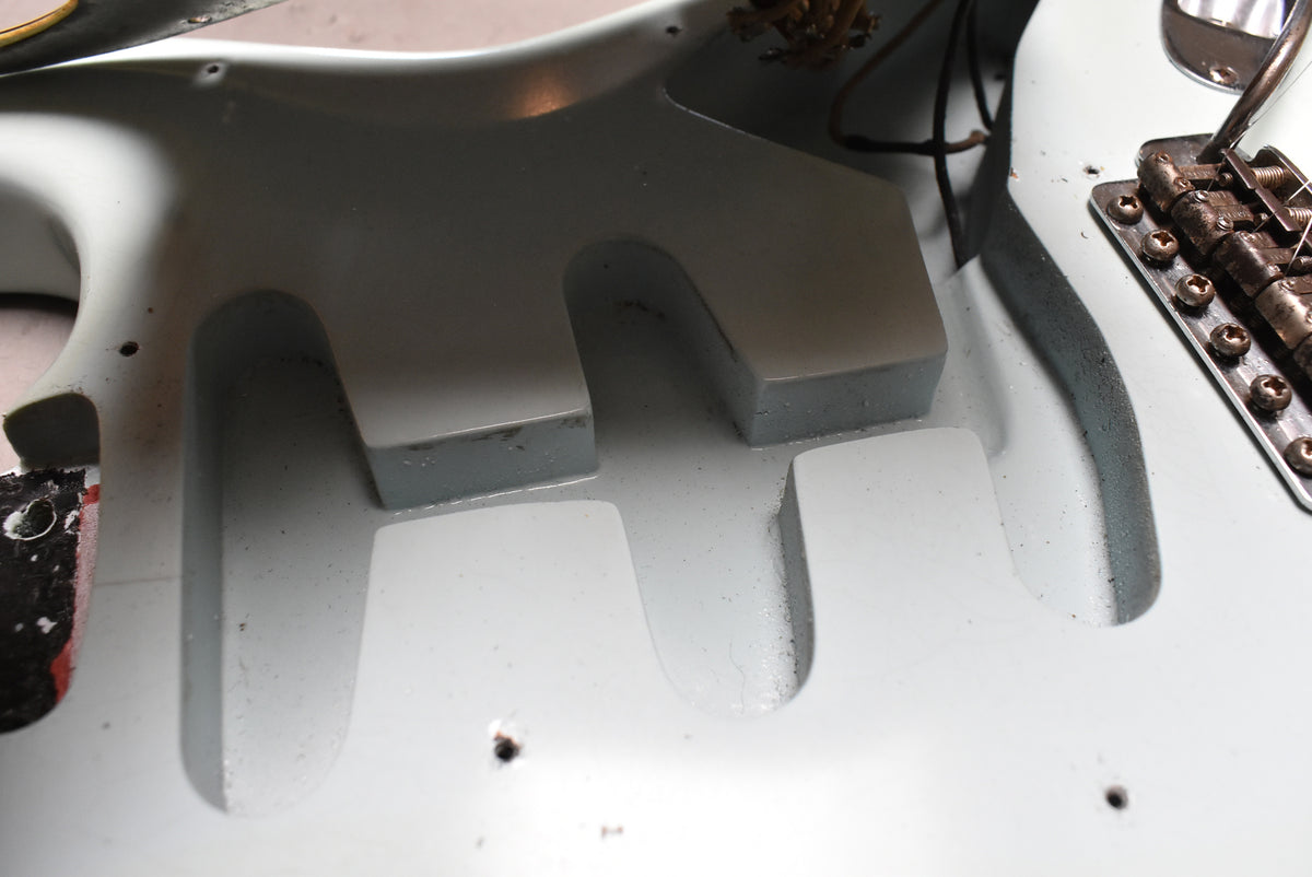 Close-up of the guitar body's pickup cavities, showing the aged sonic blue finish and some dark wiring near the bridge.