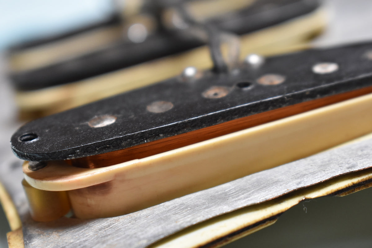 Close-up of a single-coil pickup, showing the copper wire coil, black bobbin top, and cream-colored bottom.