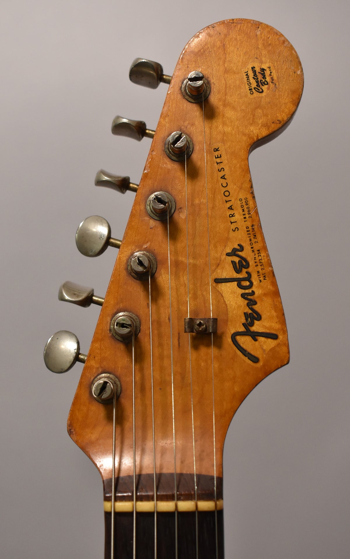 The guitar's headstock is angled slightly left, showing six aged nickel tuners, a string tree, and a dark rosewood fretboard.