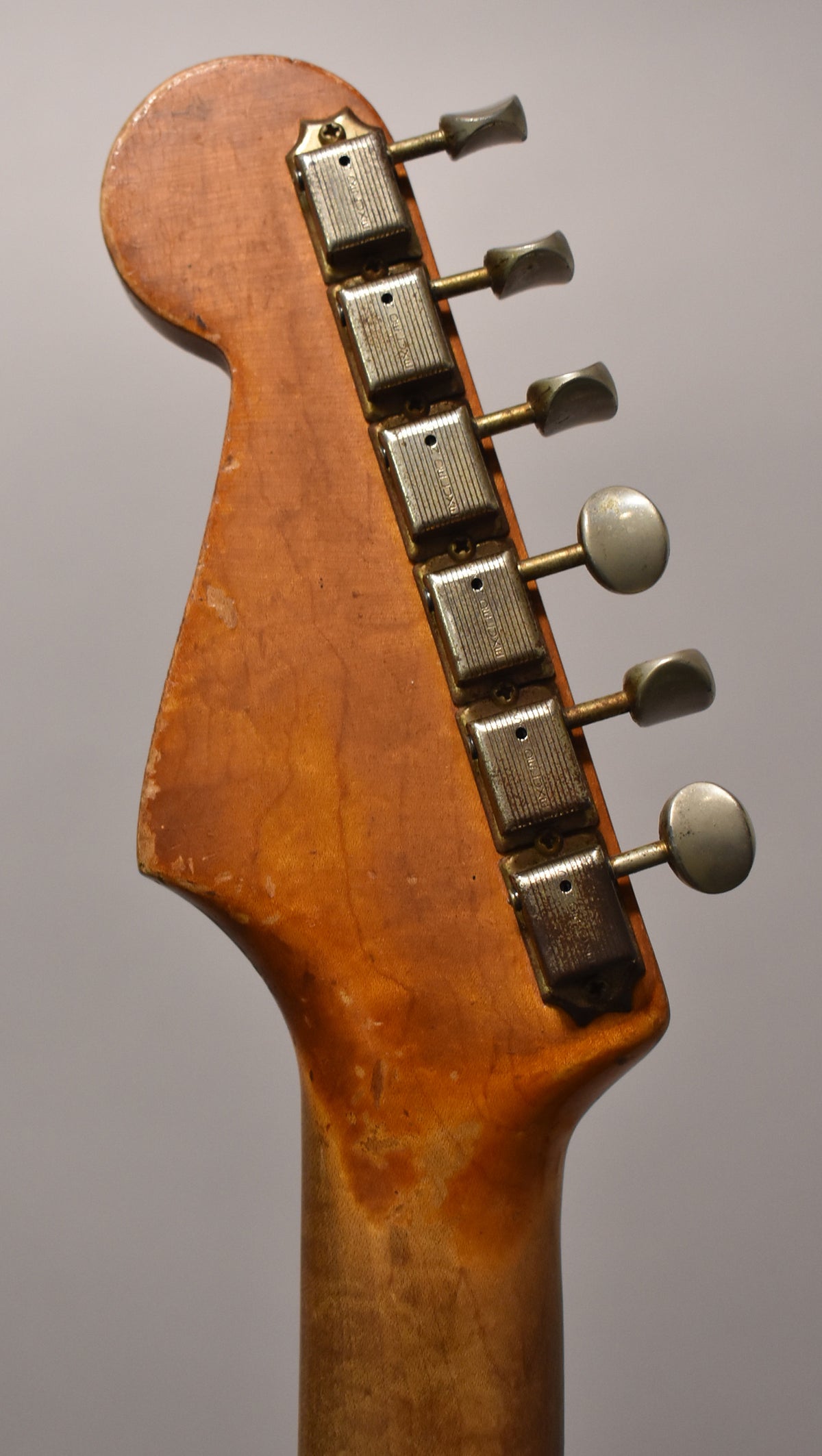 The guitar's headstock and top of the neck, showing six aged nickel tuners and heavy wear on the wood finish.