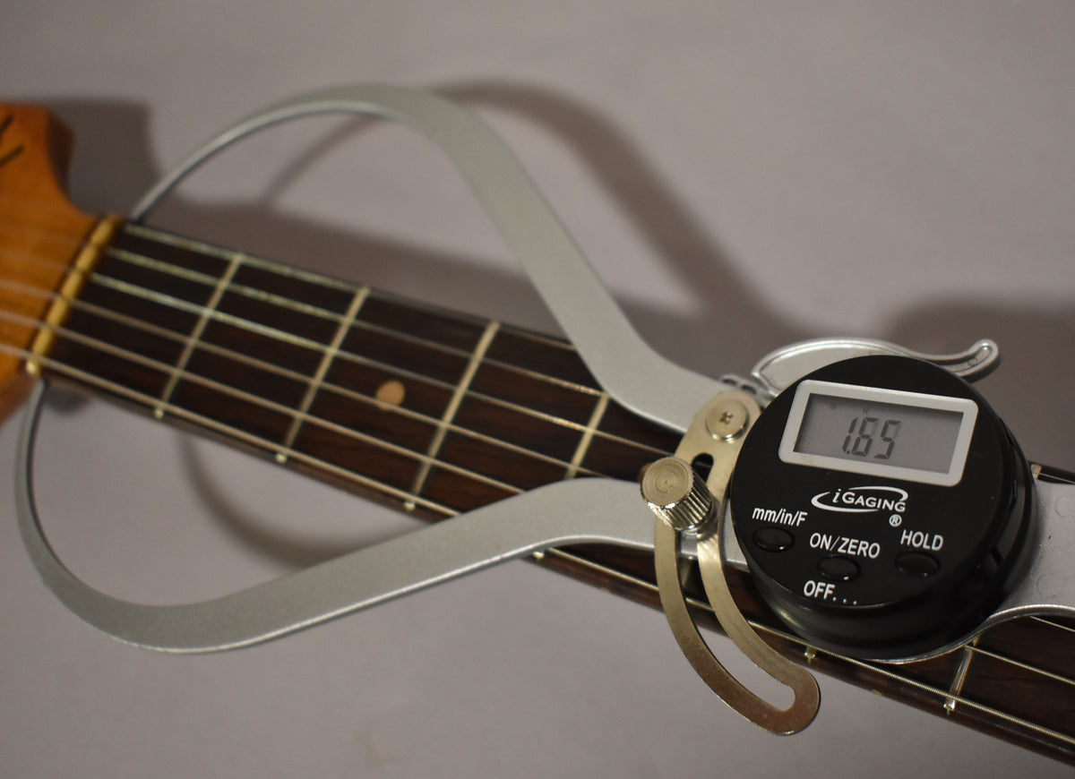 A digital caliper measures the dark rosewood fretboard at 1.89, with light fret wear and a single dot inlay visible.