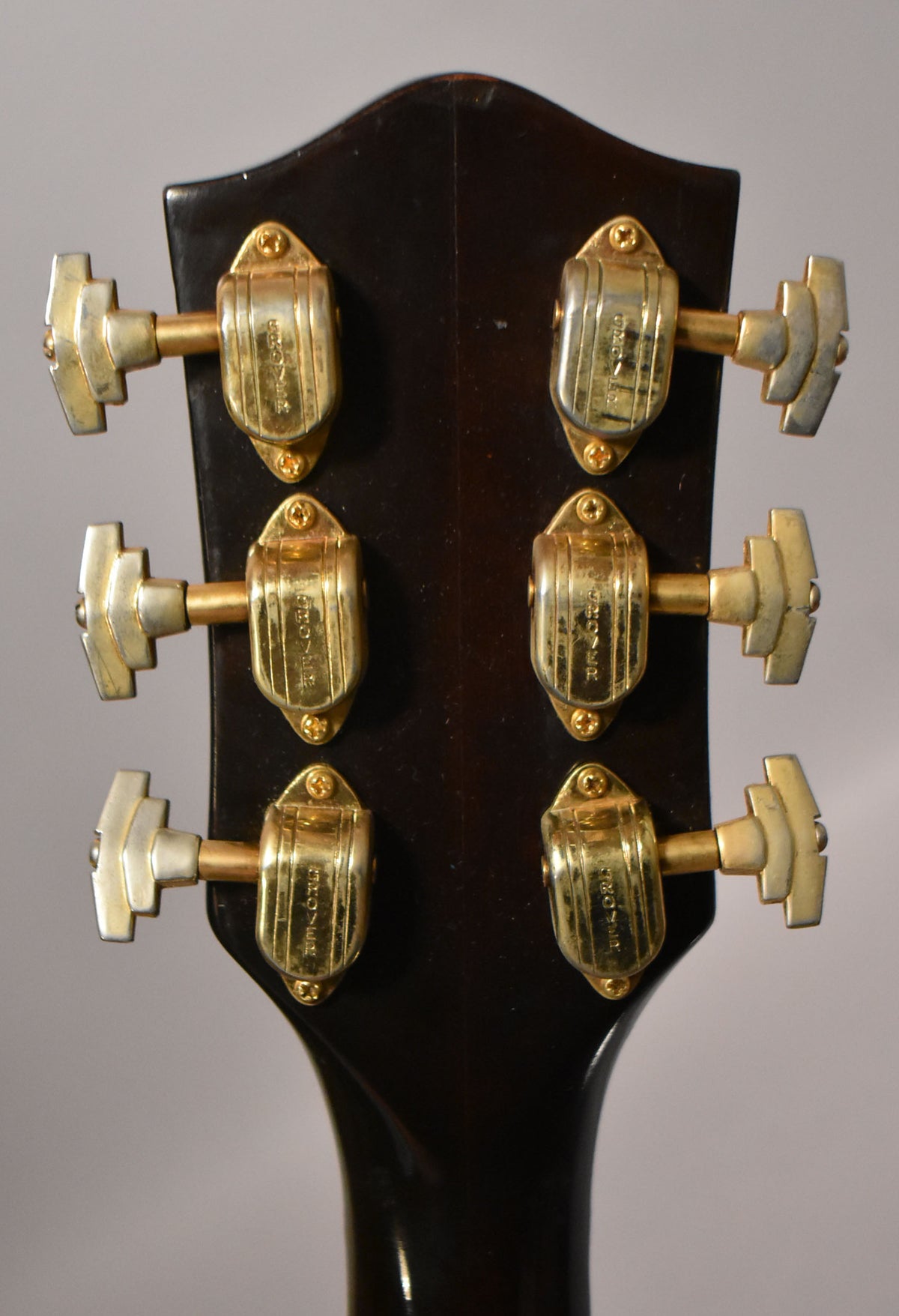 Rear view of the dark walnut headstock with six gold-plated tuners, showing visible wear and tarnishing on the hardware.