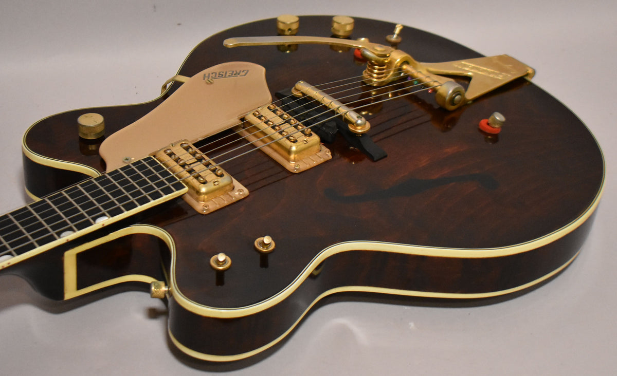 Upper body of a dark walnut hollow-body guitar with gold hardware, including a Bigsby vibrato and two humbuckers.