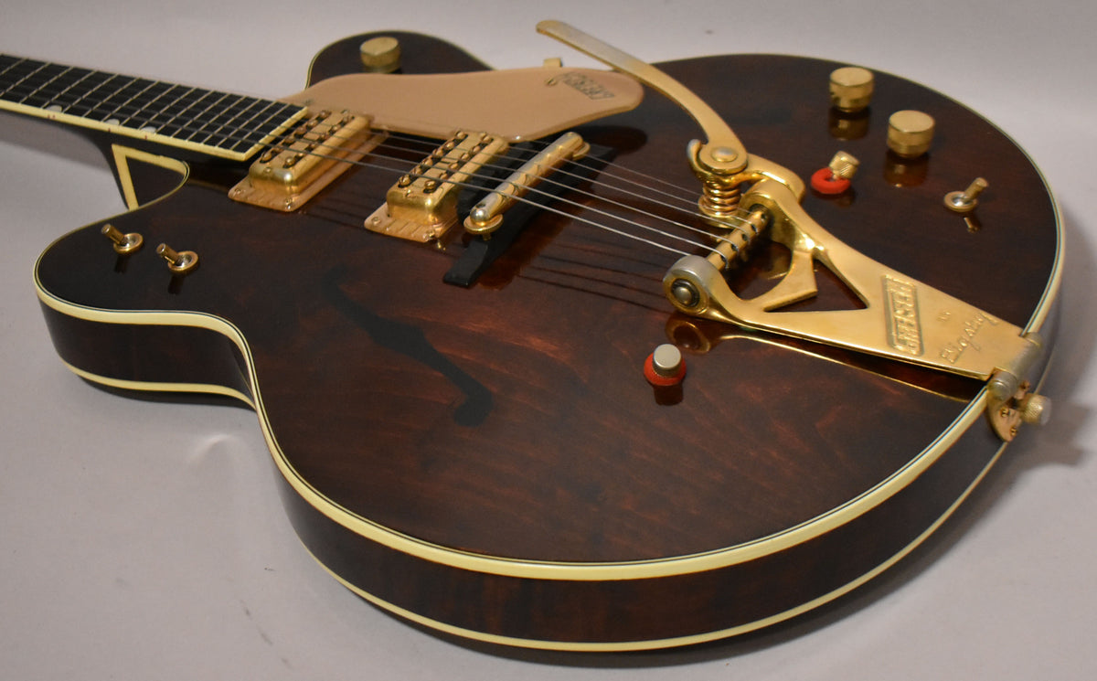 Close-up of the dark walnut hollow body, showing gold hardware, f-holes, pickguard, and Bigsby vibrato with some tarnishing.