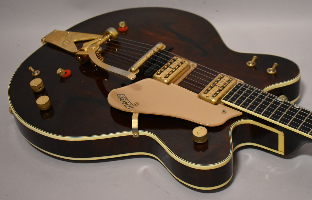 Dark walnut hollow body electric guitar, angled view of the body, showing gold hardware, cream binding, and a beige pickguard.
