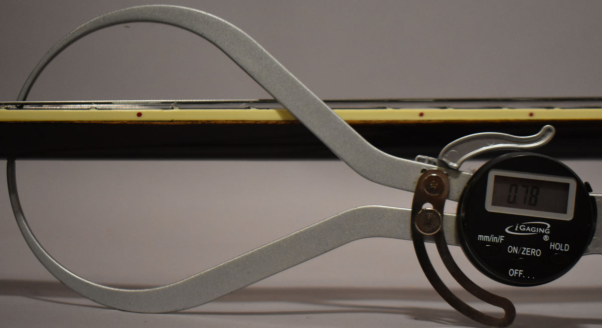 A digital caliper measures the guitar's dark brown neck and cream binding, showing a reading of 0.78.