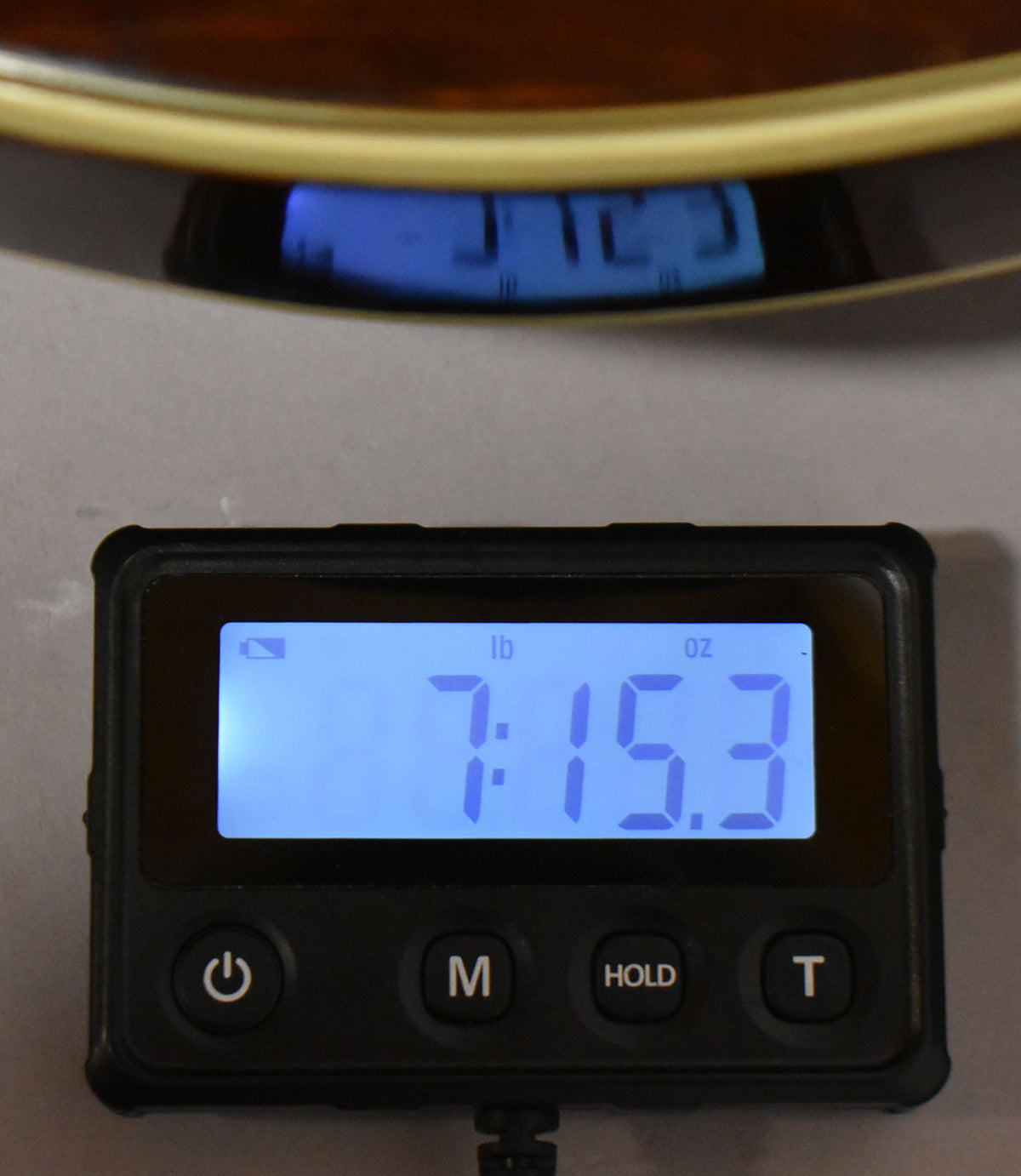 A digital scale shows the guitar weighs 7 pounds, 15.3 ounces, with a reflection of the guitar's dark walnut finish above.