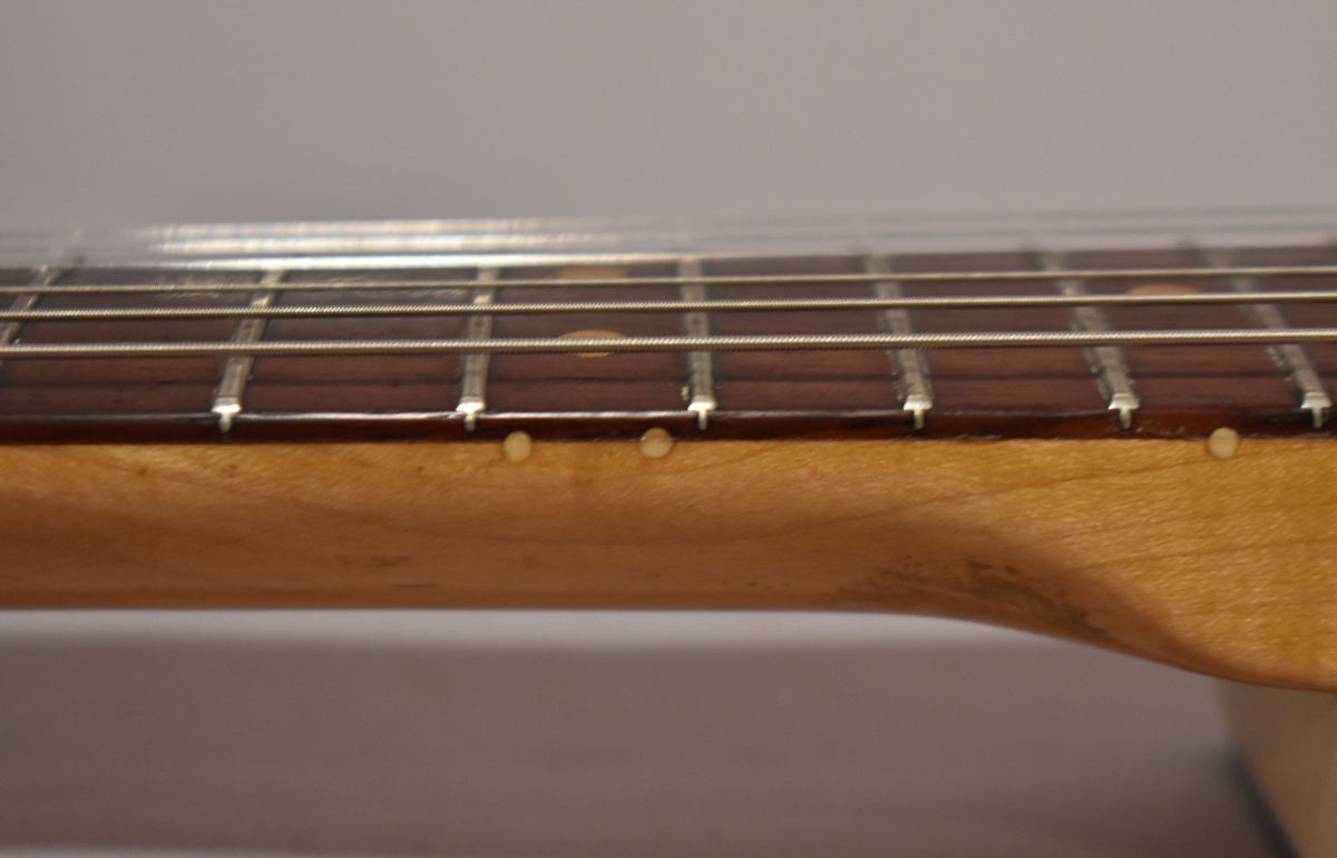 Close-up of the guitar's maple neck and dark fretboard with light dot inlays, showing wear and discoloration on the neck's finish.