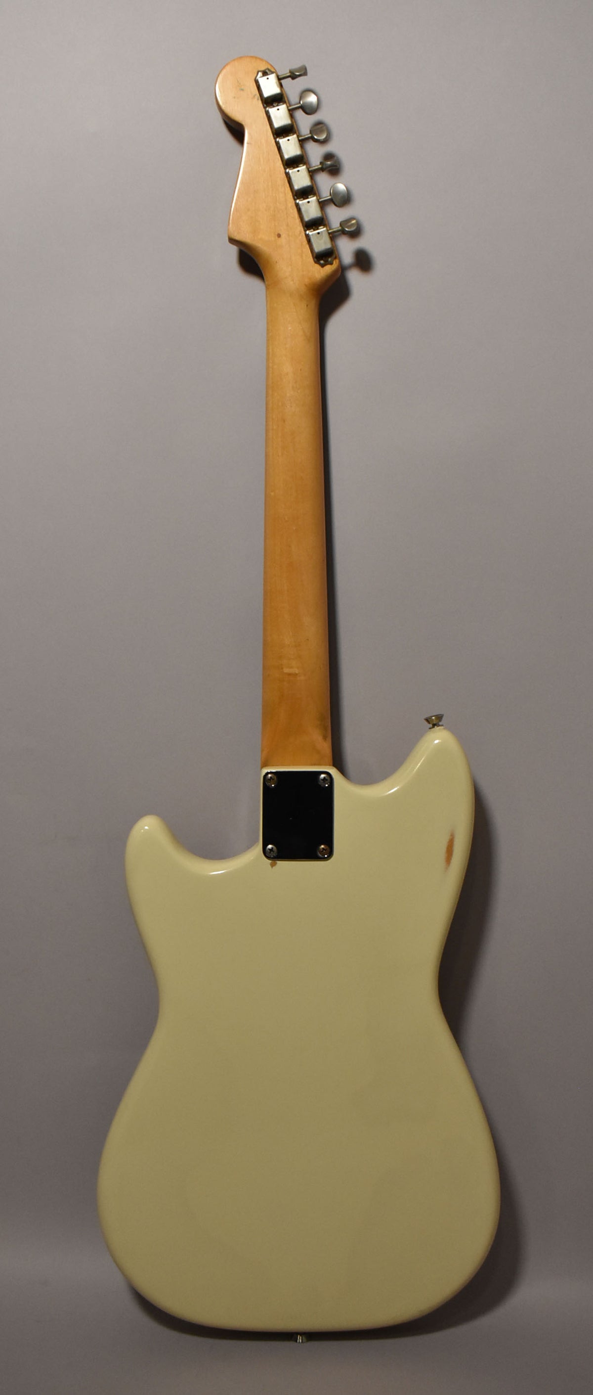 The back of a white refinished electric guitar, showing the light wood neck, six tuners, and wear on the upper horn.