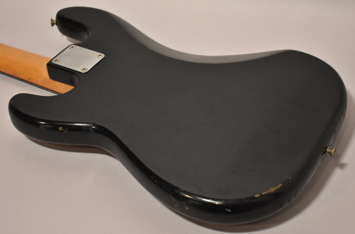 The black bass body, viewed from the back, shows a satin finish with gloss edges and significant wear on the lower bout.