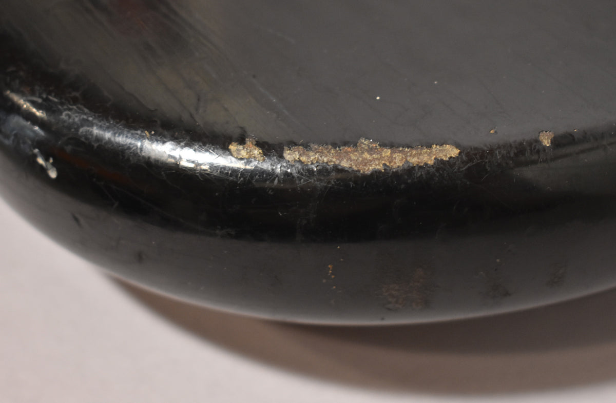 Close-up of the bass's black body edge, showing heavy wear and flaking paint revealing a brown layer underneath.