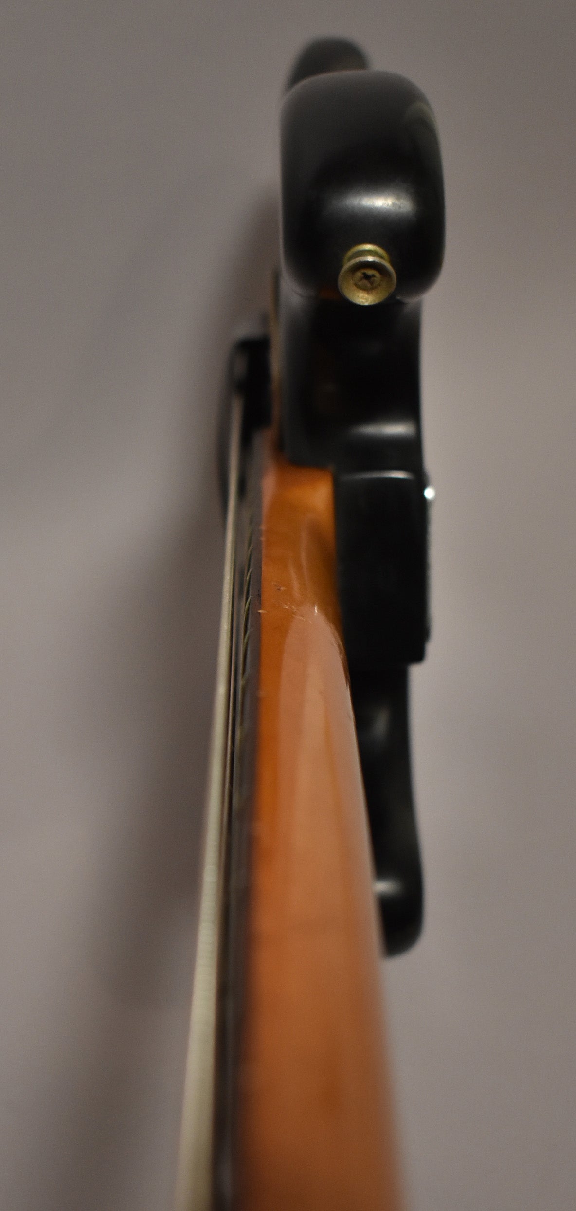 The black bass body is seen from above, with the neck extending left, showing a light brown finish and some wear.