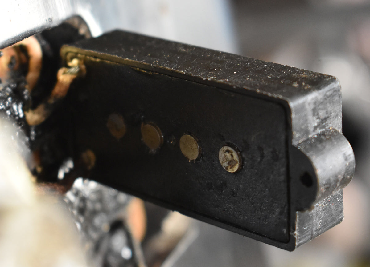 Close-up of the black split-coil pickup, showing four worn gold pole pieces and a mounting screw, with some wiring visible.