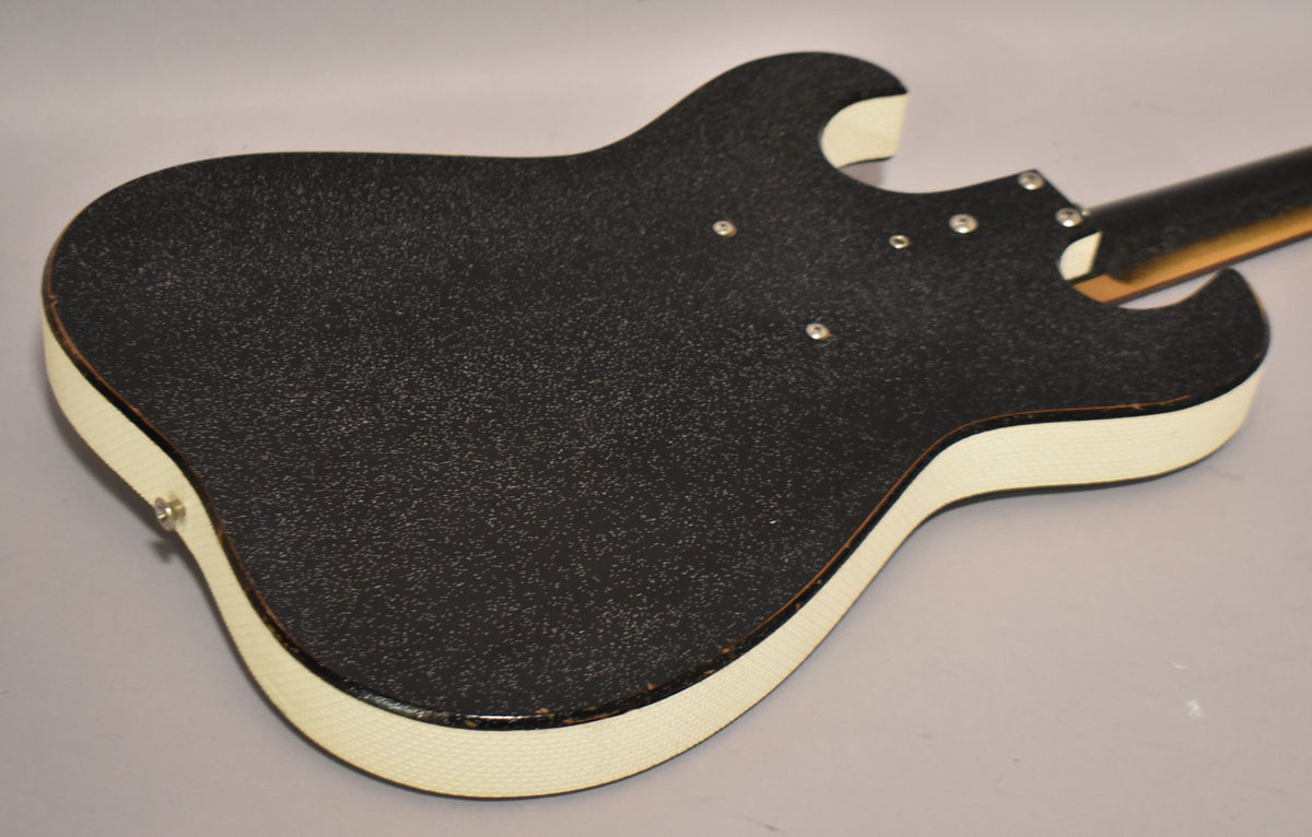 The guitar's back, covered in black textured material with white binding, shows a few small dings and four visible screws.