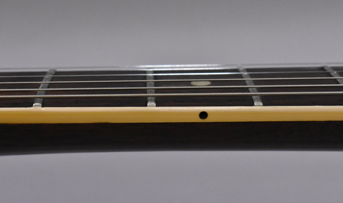 Close-up of the guitar's dark fretboard and light binding, showing strings, frets, and a single black side dot marker.