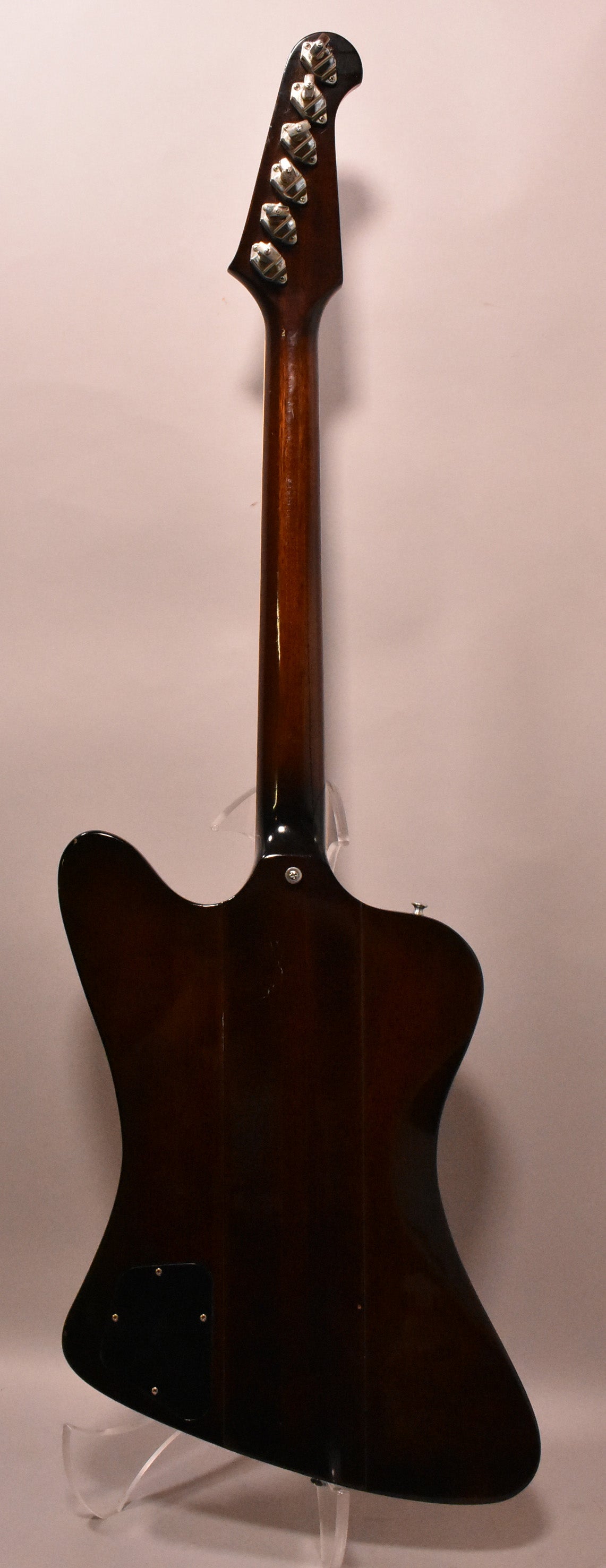The back of a dark sunburst Firebird guitar, showing the neck, headstock with six tuners, and control cavity cover.