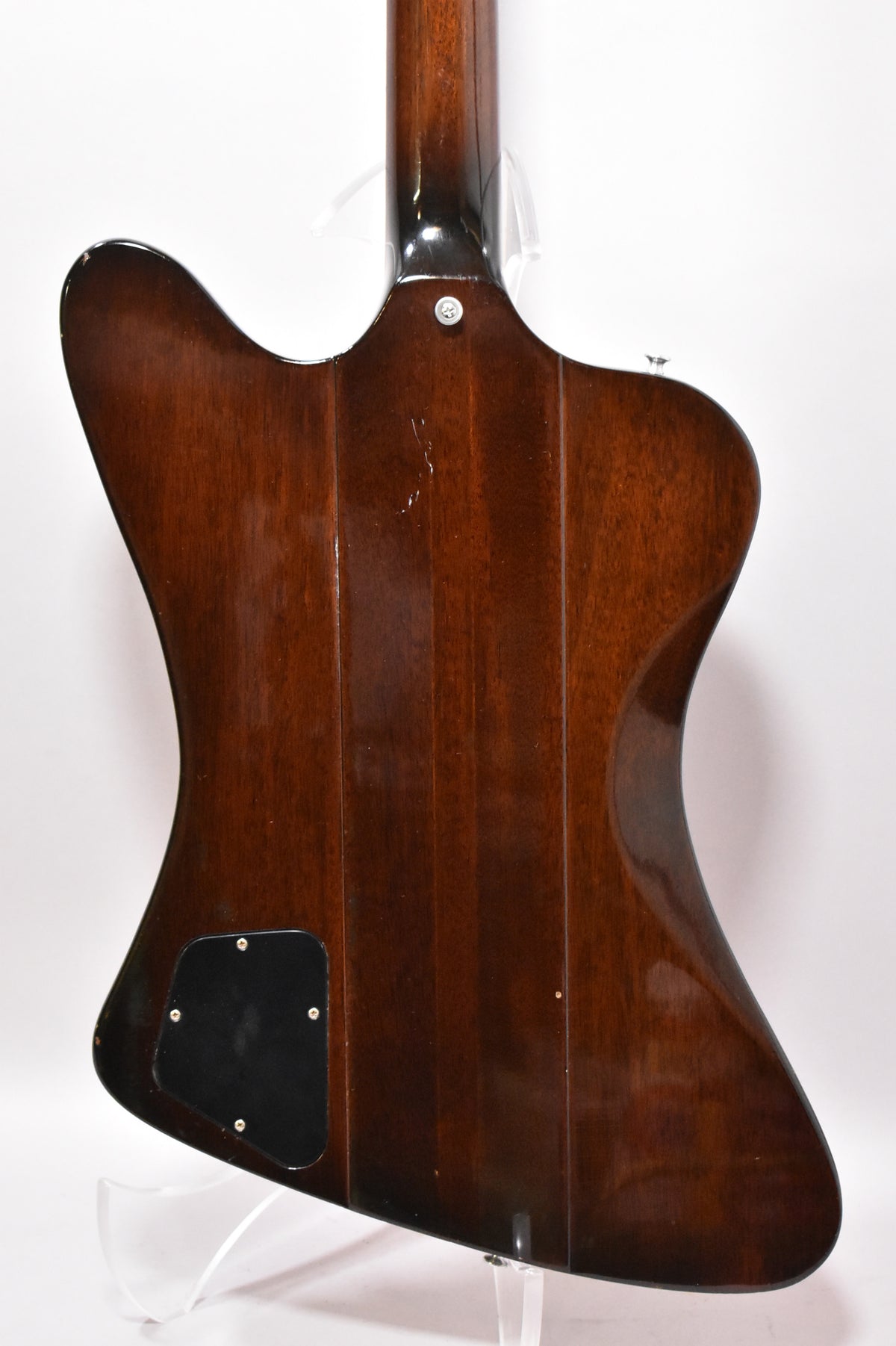 The back of the dark sunburst guitar shows a black control plate, a strap button, and light scratches on the body and neck heel.