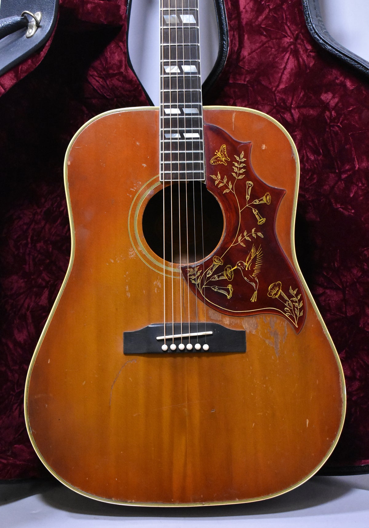 Full front view of a sunburst acoustic guitar, showing the body, soundhole, bridge, and lower fretboard with rectangular inlays.
