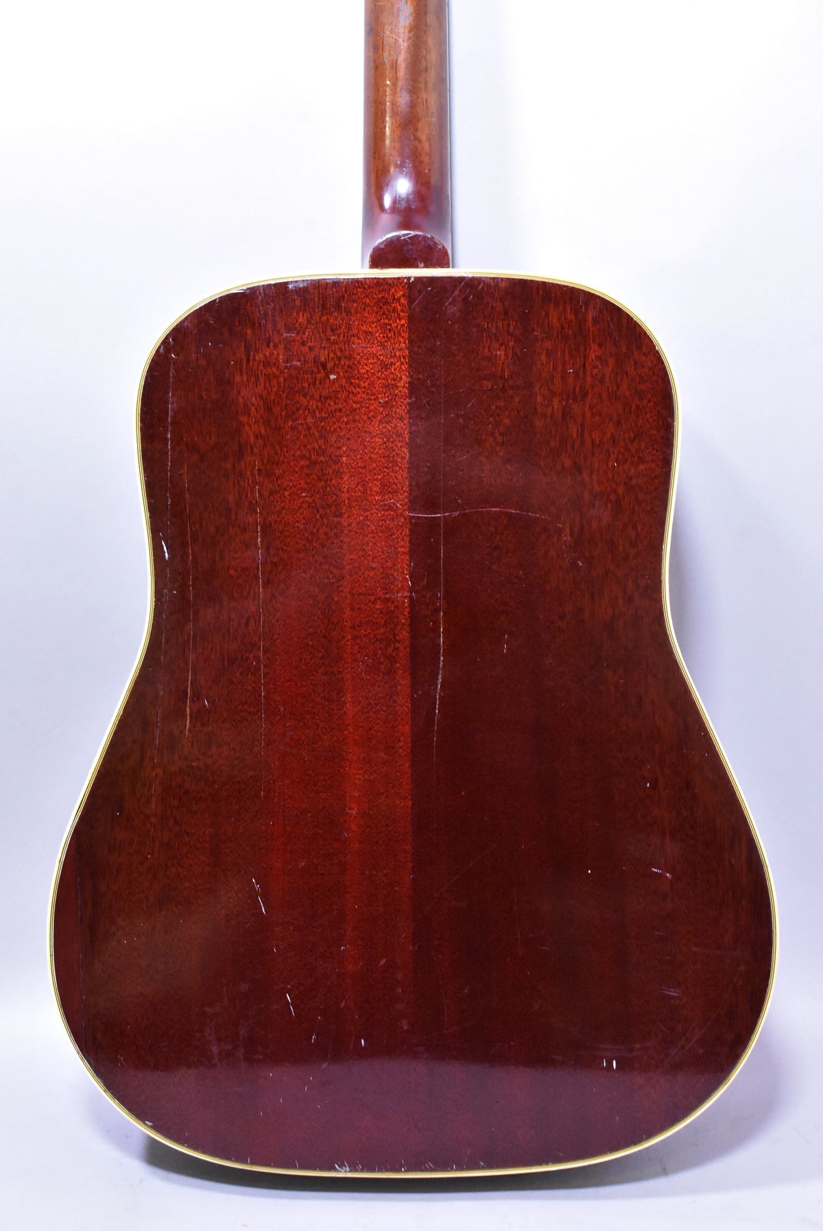 The guitar's dark sunburst back and neck are visible, showing extensive finish checking, scratches, and dings, with cream binding.