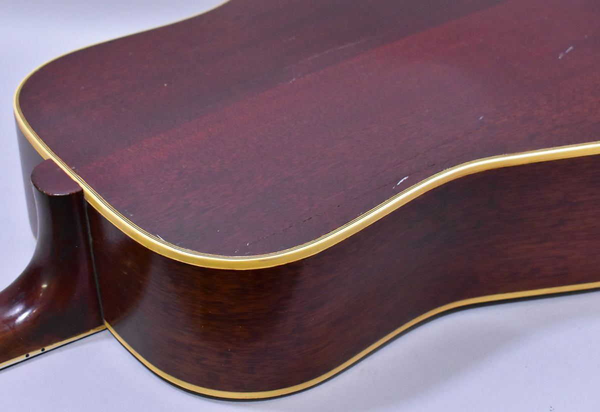 Close-up of the guitar's lower bout and neck heel, showing the dark sunburst finish, cream binding, and minor surface wear.