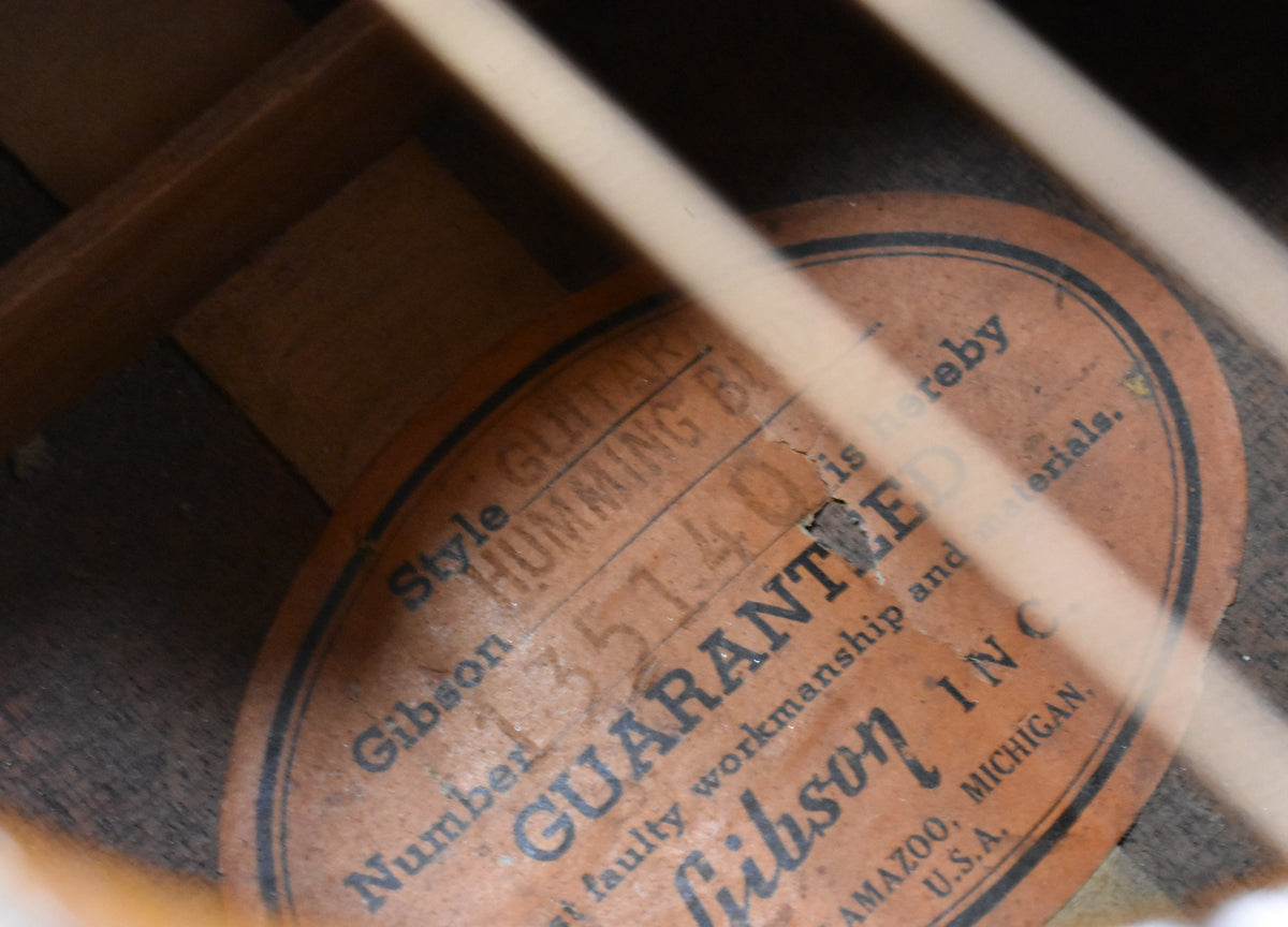 Close-up inside the soundhole, showing the oval orange label with black text, partially obscured by internal bracing and wear.