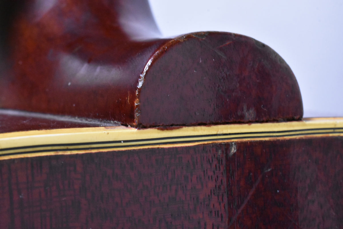 Close-up of the guitar's dark cherry neck heel, showing finish wear and chipping where it meets the body's cream and black binding.