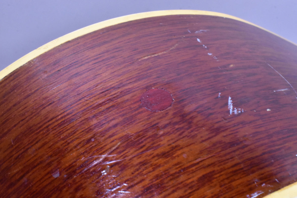 Close-up of the guitar's lower bout, showing the dark sunburst finish with a circular red spot, surrounded by numerous scratches and wear.