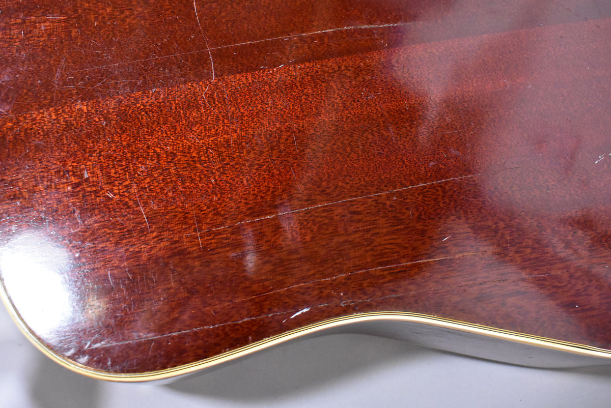 Close-up of the guitar's lower bout, showing the dark reddish-brown sunburst finish with extensive checking, scratches, and wear.