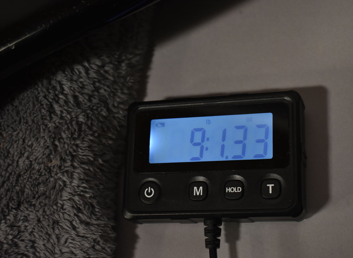 A digital scale displays "9:13.3" in pounds and ounces, with a fuzzy gray surface to the left.