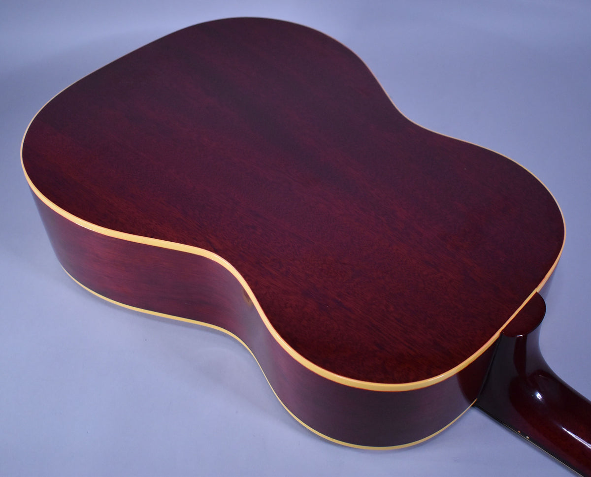 The back and side of a dark cherry sunburst acoustic guitar with cream binding, showing light wear and wood grain.
