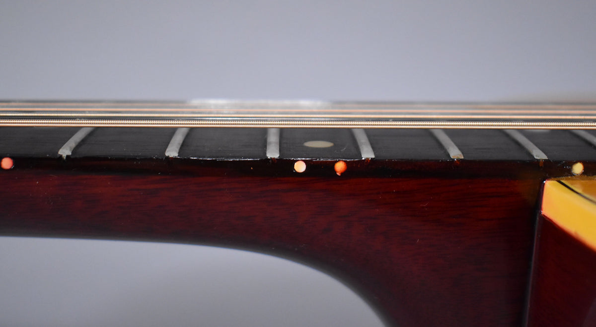 Close-up of the guitar's dark fretboard and neck, showing wear along the fret edges and a single circular inlay at the 7th fret.