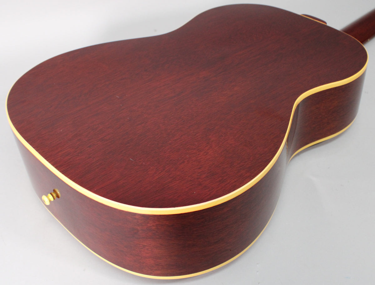 The back and side of a reddish-brown acoustic guitar with cream binding, showing three visible input jacks on the lower bout.