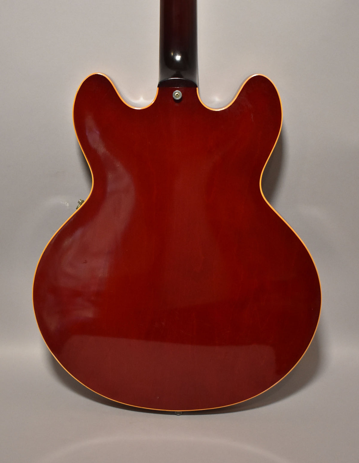 Full rear view of a cherry red hollowbody guitar with a dark neck, showing light surface scratches and binding.